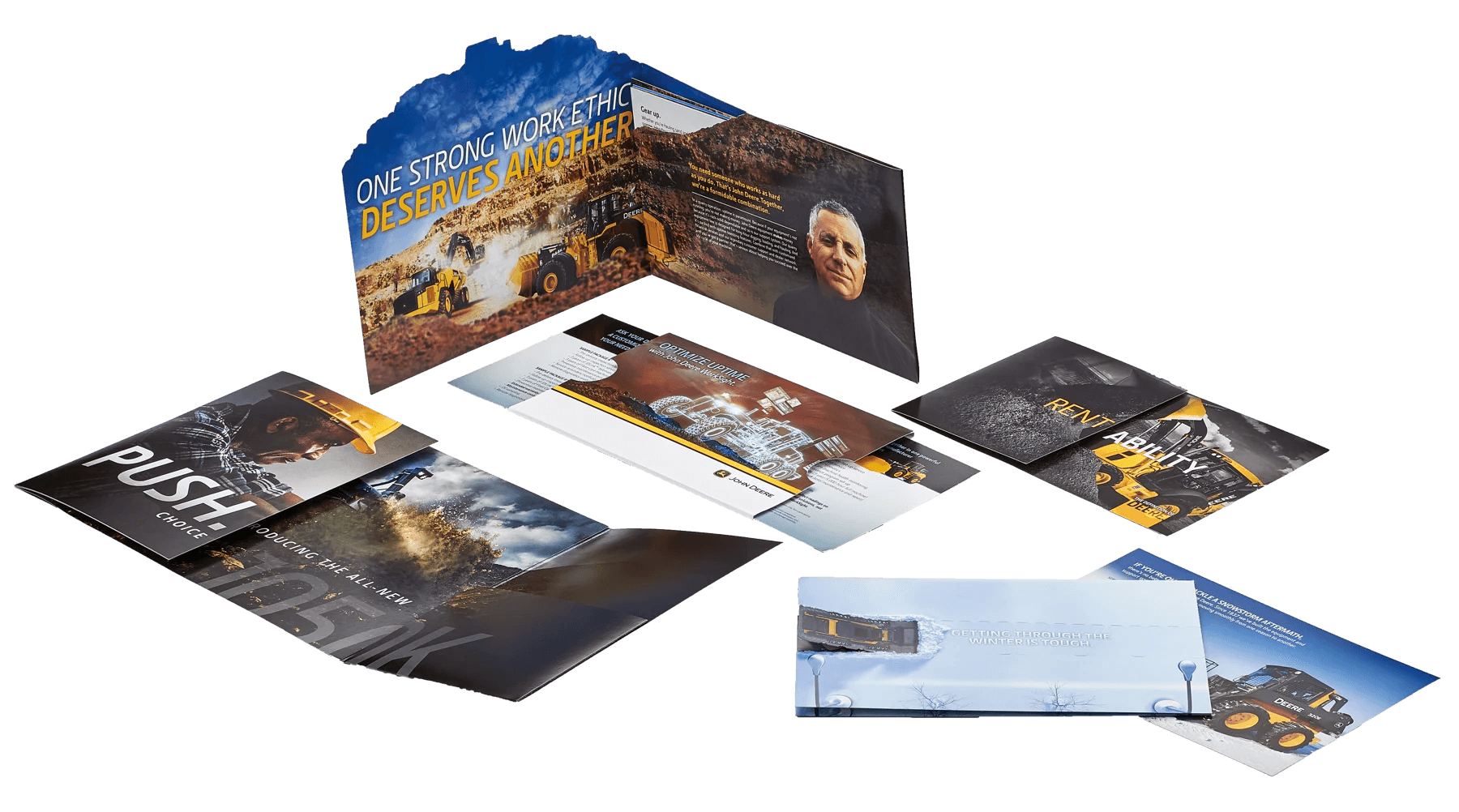 A collection of construction equipment-themed commercial brochures laid out on a dark surface, with a focus on heavy machinery, work ethic, and winter operability.