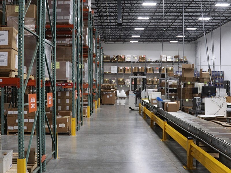 Interior of a warehouse with shelves full of boxes and a conveyor belt.